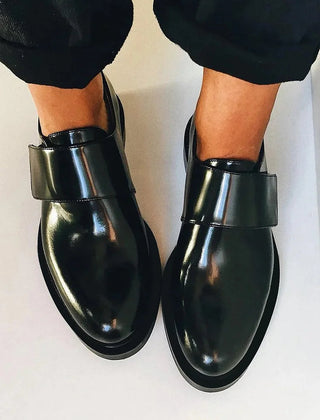 Black polished strap loafers with glossy finish and clean strap detail