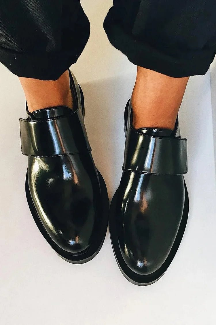 Black polished strap loafers with glossy finish and clean strap detail