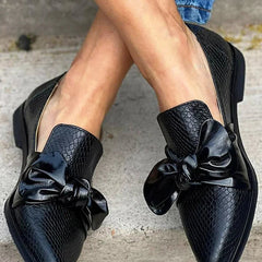 Black loafer with textured finish and a bold shiny bow detail