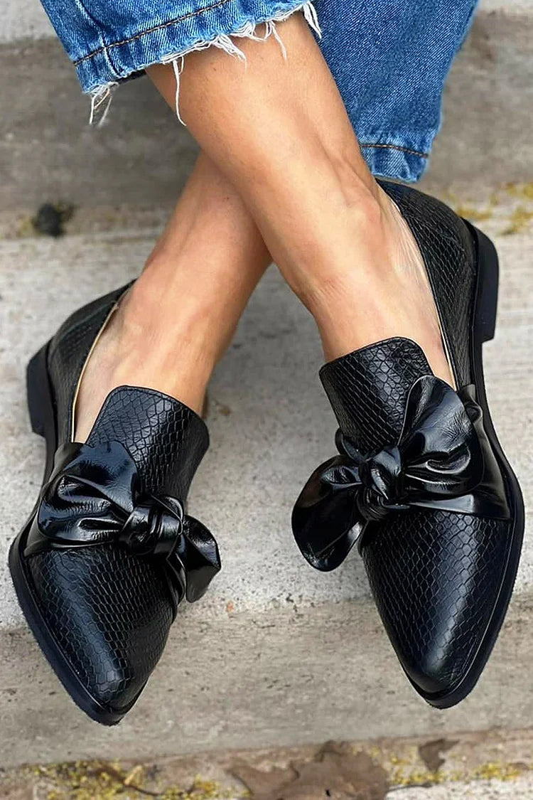 Black loafer with textured finish and a bold shiny bow detail