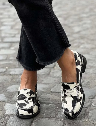 Black and white cow-print slip-on loafers with a classic rounded silhouette