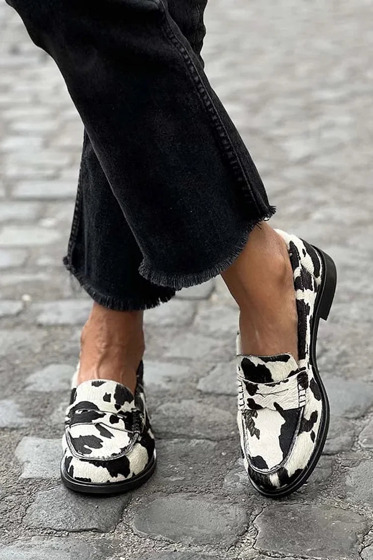 Black and white cow-print slip-on loafers with a classic rounded silhouette
