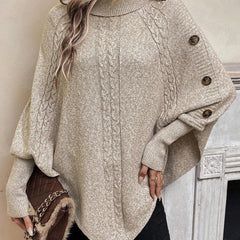 High neck batwing poncho sweater in cable knit with asymmetrical hem and button shoulder detail