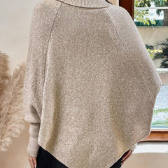 High neck batwing poncho sweater in cable knit with asymmetrical hem and button shoulder detail