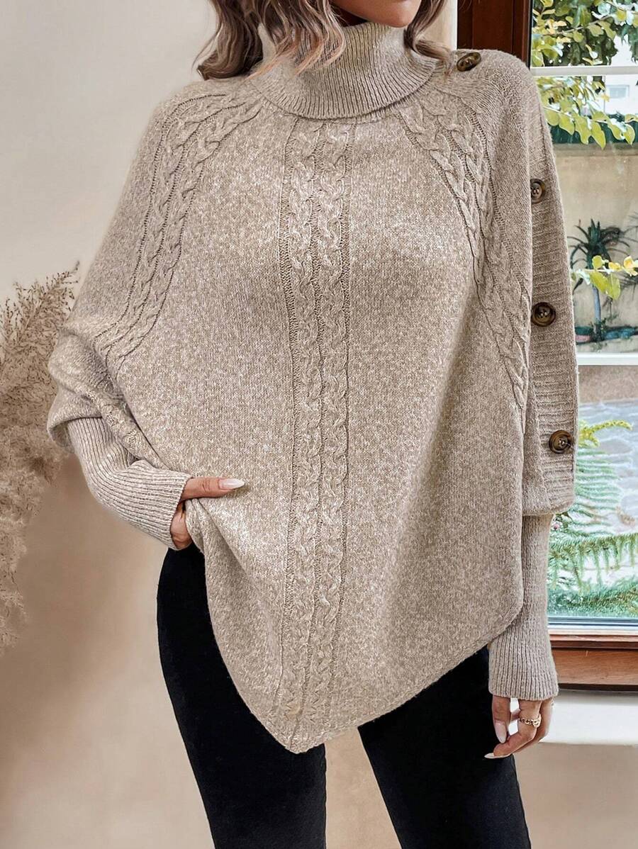 High neck batwing poncho sweater in cable knit with asymmetrical hem and button shoulder detail