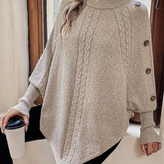 High neck batwing poncho sweater in cable knit with asymmetrical hem and button shoulder detail