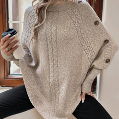 High neck batwing poncho sweater in cable knit with asymmetrical hem and button shoulder detail
