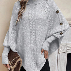 High neck batwing poncho sweater in cable knit with asymmetrical hem and button shoulder detail