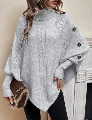 High neck batwing poncho sweater in cable knit with asymmetrical hem and button shoulder detail