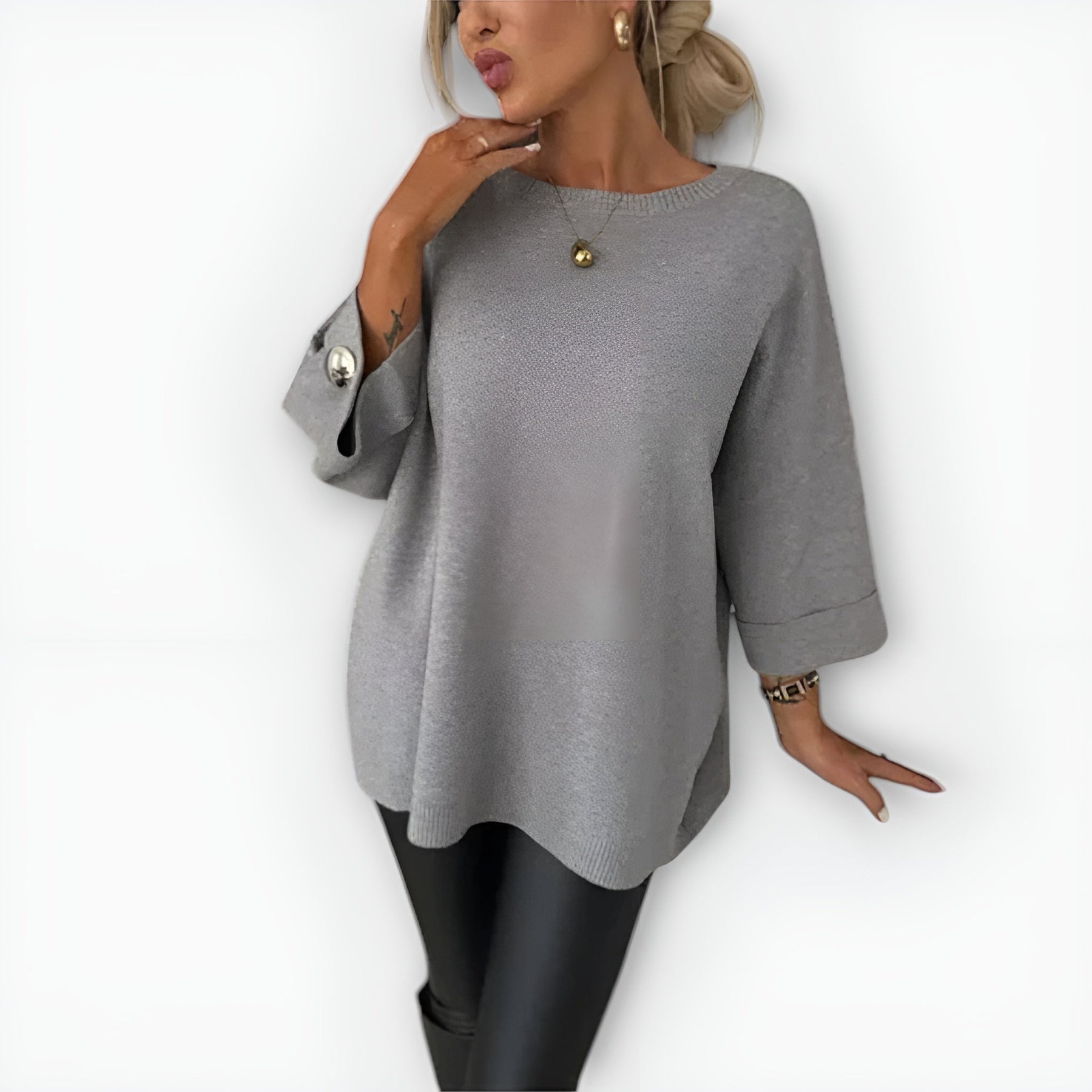 Oversized women's sweater with round neckline, three-quarter sleeves and button-detailed cuffs