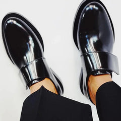 Black polished strap loafers with glossy finish and clean strap detail