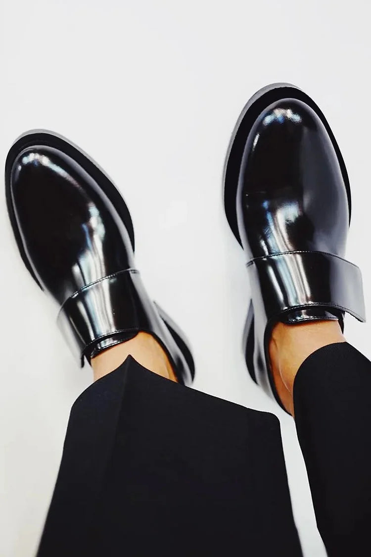 Black polished strap loafers with glossy finish and clean strap detail