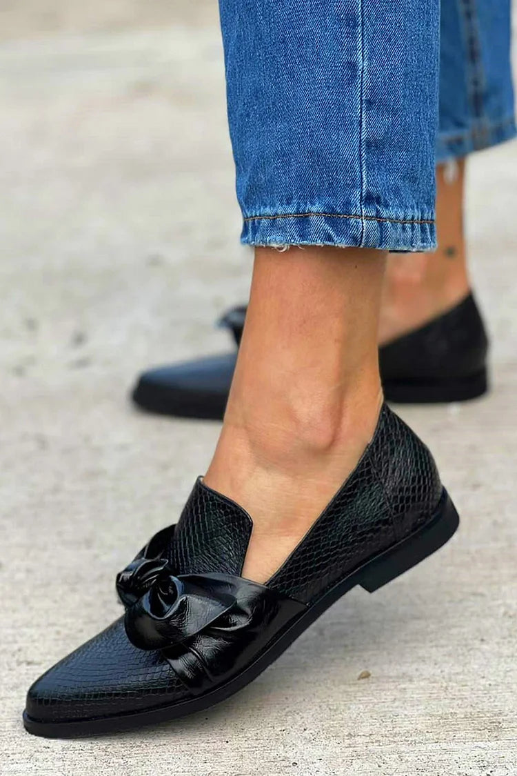 Black loafer with textured finish and a bold shiny bow detail