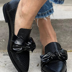 Black loafer with textured finish and a bold shiny bow detail