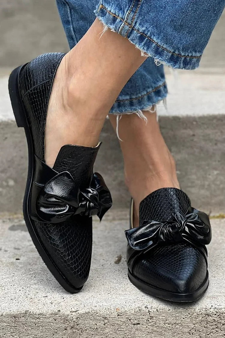 Black loafer with textured finish and a bold shiny bow detail