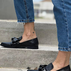 Black loafer with textured finish and a bold shiny bow detail