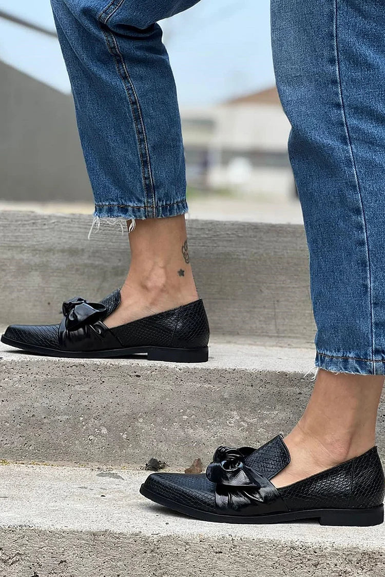 Black loafer with textured finish and a bold shiny bow detail