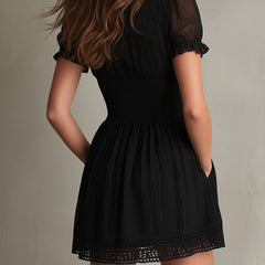 Black smocked mini dress with delicate lace trim at neckline and hem