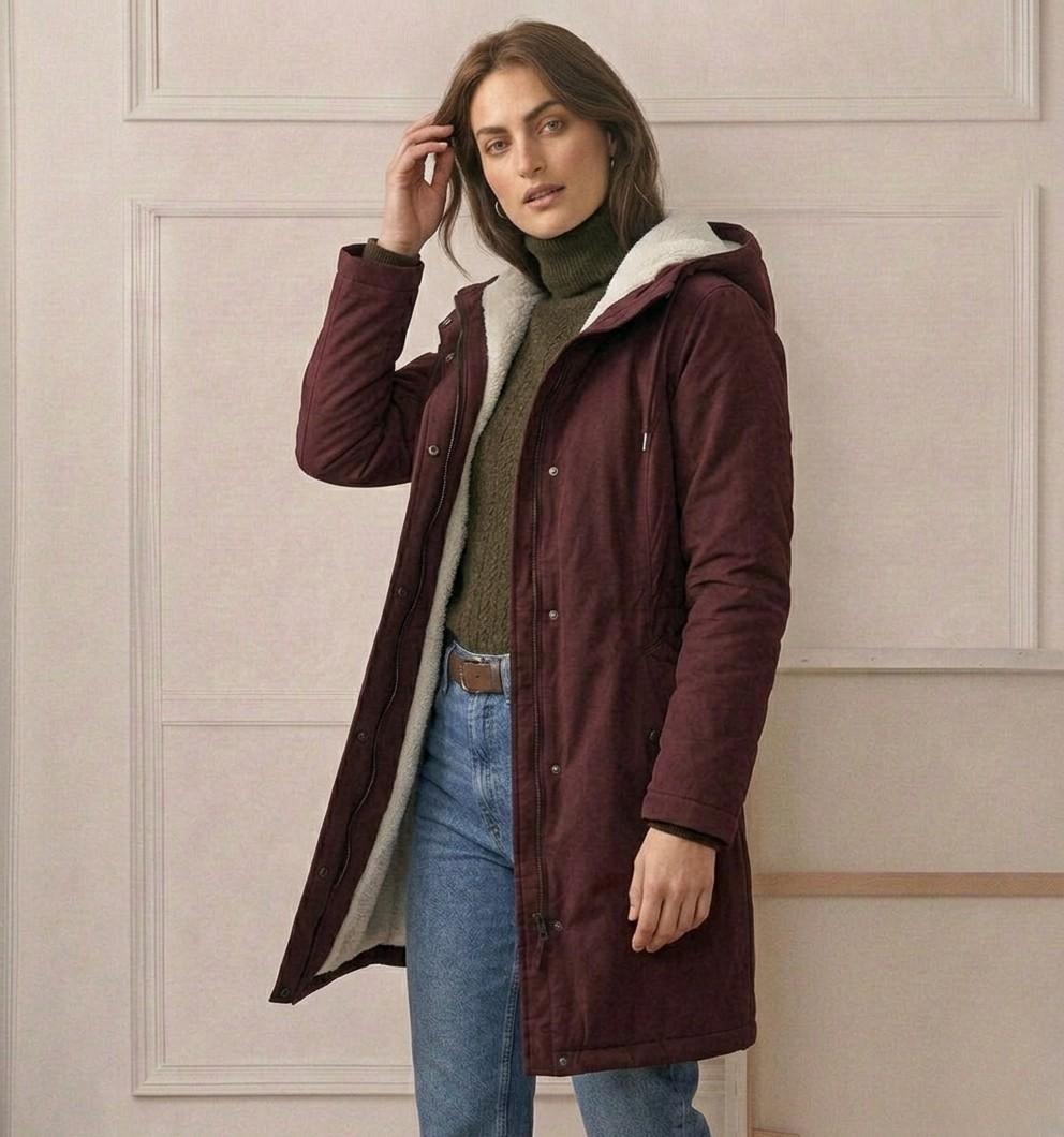 Woman wearing a cozy hooded longline weatherproof coat with plush lining and front pockets