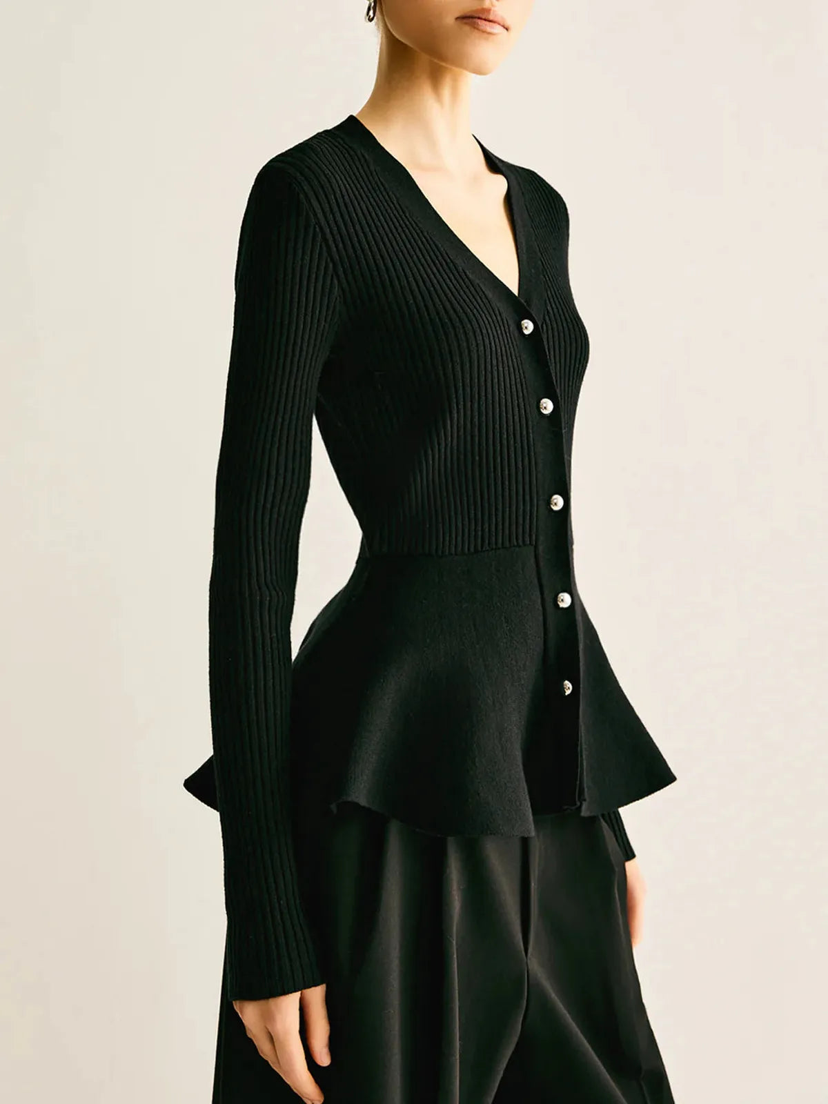 Black ribbed peplum knit top with metallic button detailing and fitted waist
