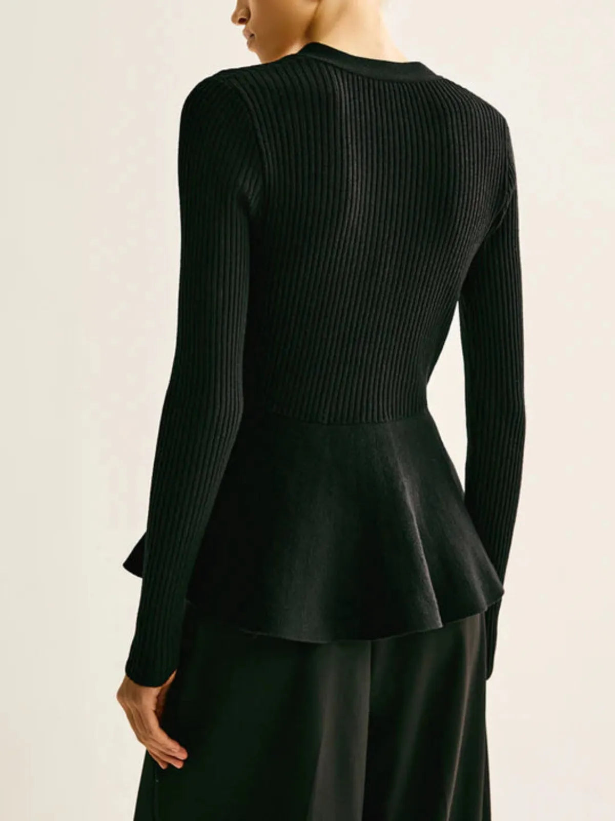 Black ribbed peplum knit top with metallic button detailing and fitted waist