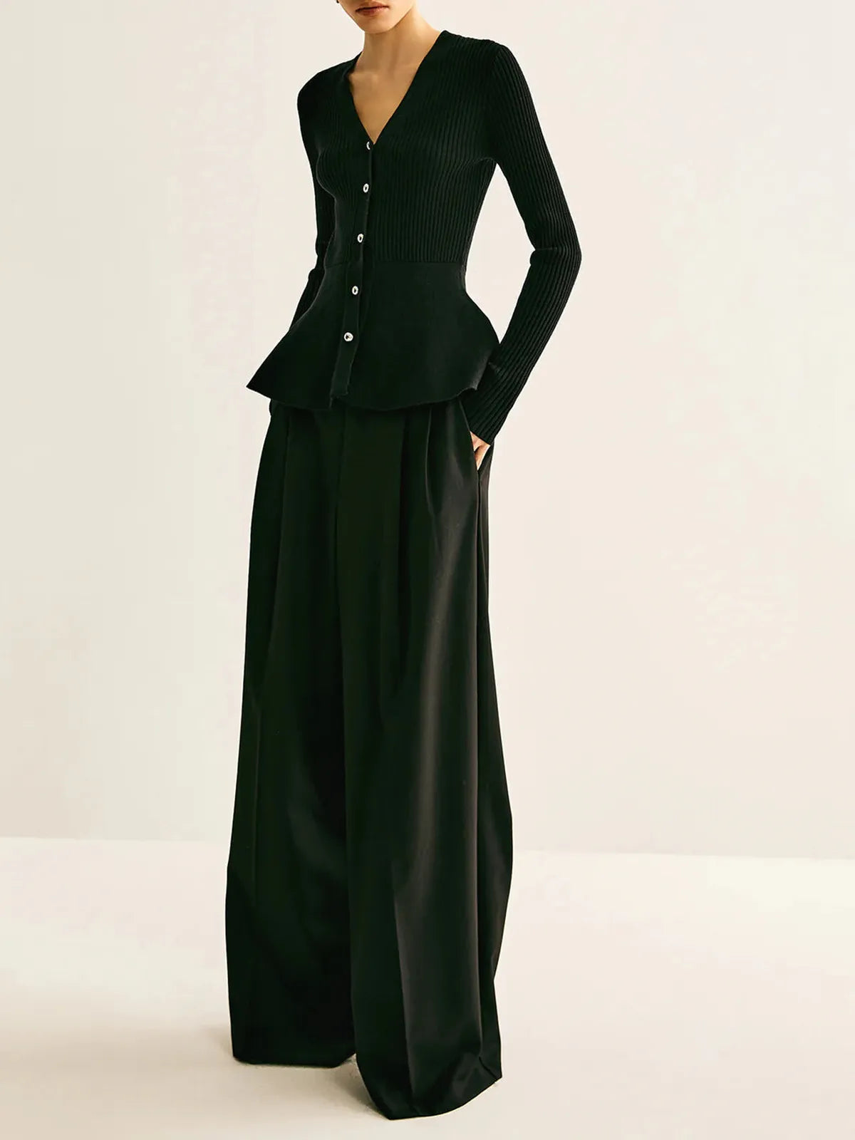 Black ribbed peplum knit top with metallic button detailing and fitted waist