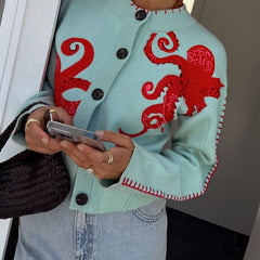 Light blue women's button-front cardigan with a bold octopus pattern across the front and sleeves