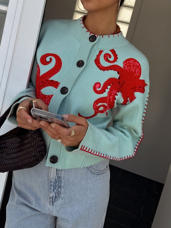 Light blue women's button-front cardigan with a bold octopus pattern across the front and sleeves