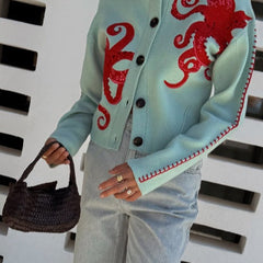 Light blue women's button-front cardigan with a bold octopus pattern across the front and sleeves