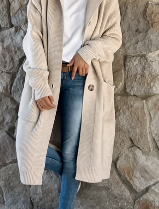 Woman wearing a long flowing knit cardigan in a neutral shade over a casual outfit