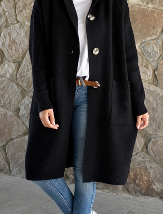 Woman wearing a long flowing knit cardigan in a neutral shade over a casual outfit