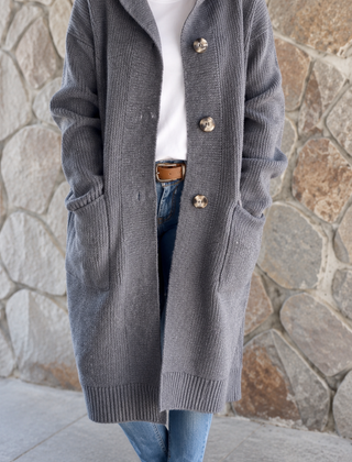 Woman wearing a long flowing knit cardigan in a neutral shade over a casual outfit