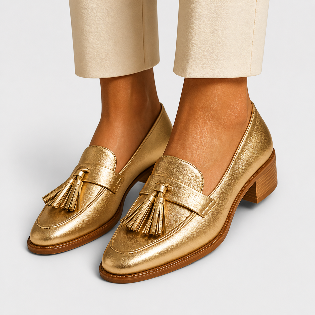 Gold-tone slip-on loafers with refined details, shown from the side