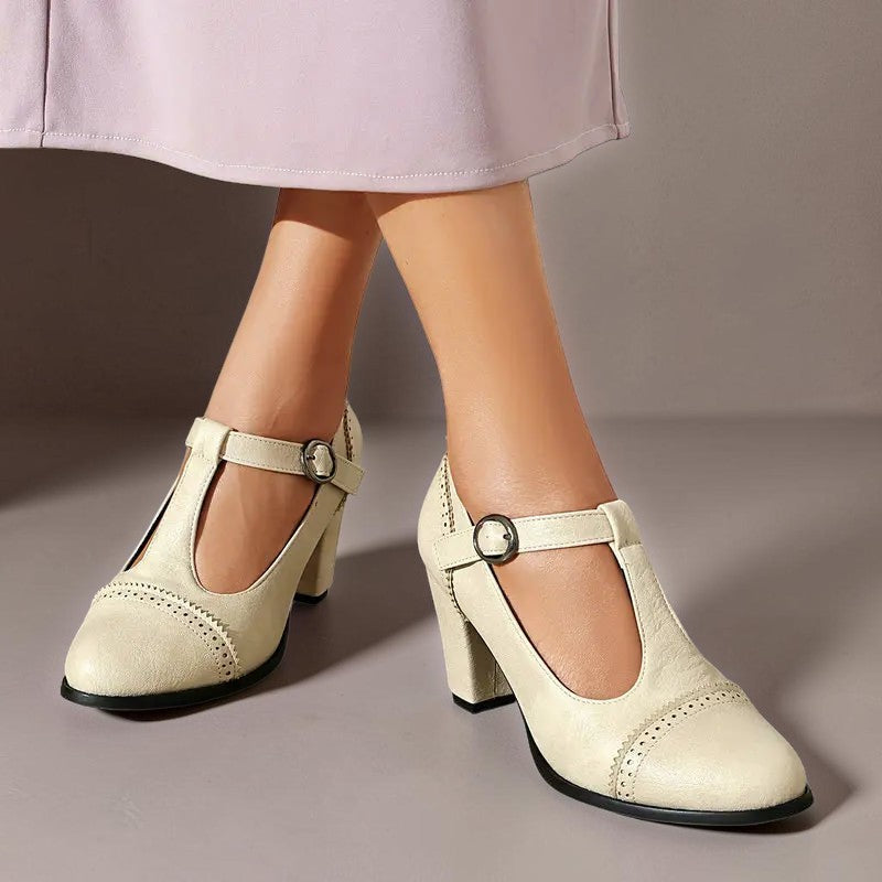 T-strap brogue heels with punched detailing on a steady block heel, shown in a neutral tone