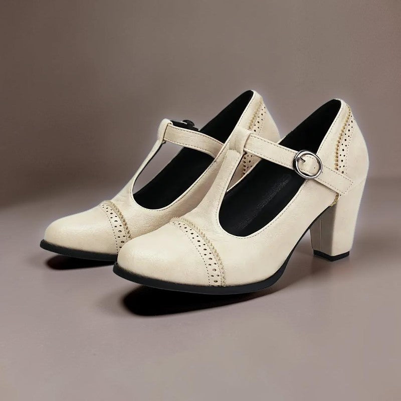 T-strap brogue heels with punched detailing on a steady block heel, shown in a neutral tone